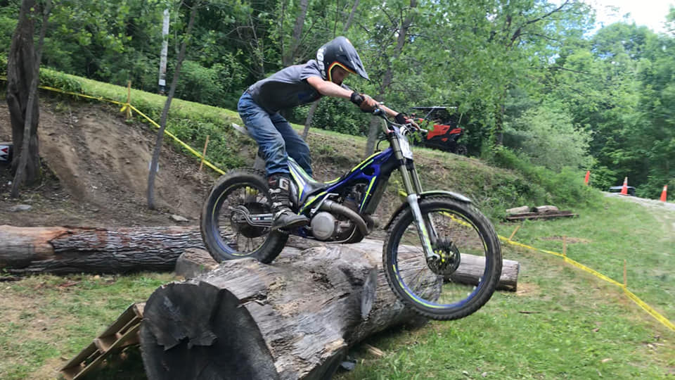 Trials riding over a log on a Sherco motorcycle